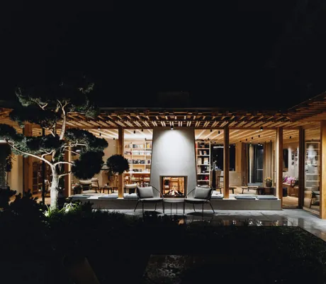 Blick vom Garten auf die Bibliothek mit Kamin des Sensoria Dolomites am Abend