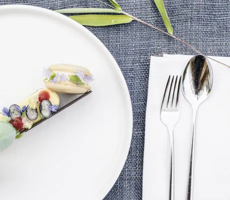 Gericht mit Macarons auf weißem Teller auf blauem Leinenset im Sensoria Dolomites