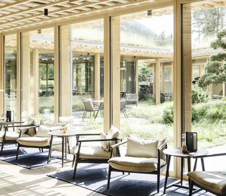 Lobby mit an 50er Jahre angelehnte Sitzmöbel und Blick auf den japanischen Garten im Sensoria Dolomites