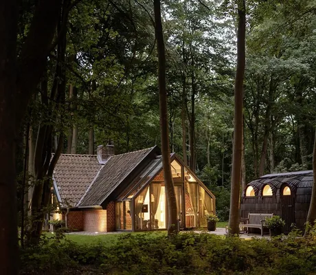 erleuchtetes Badehaus im Wald mit angrenzender Schindelsauna im WEISSENHAUS