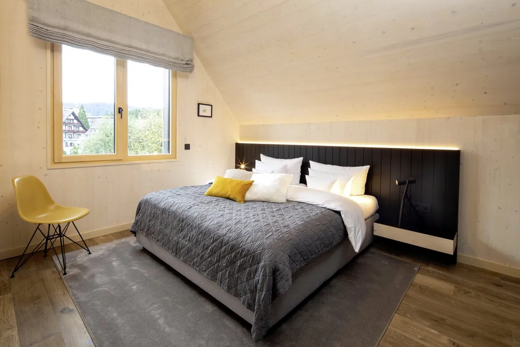 Schlafzimmer im Chalet des Hotel Engel Obertal mit gelbem Stuhl