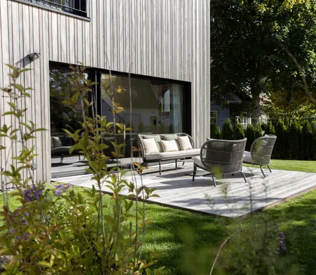 graue Korbmöbel auf der Terrasse des Chalets im Hotel Engel Obertal auf Holzplattform