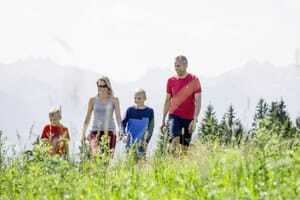 Familie mit zwei Kindern läuft im Allgäuer Berghof über die Wiese