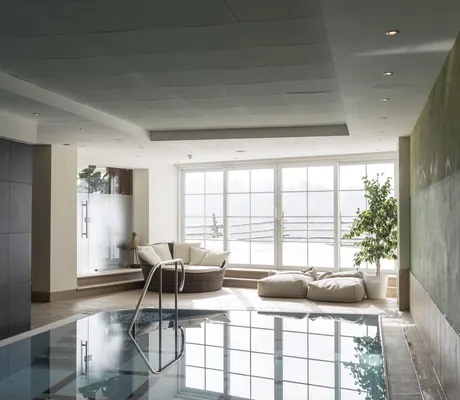 Indoorpool mit Sitzlandschaft und Ausblick im Family Adventure Hotel Maria