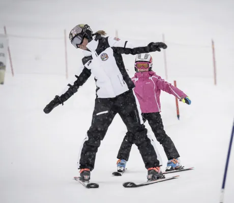 Skilehrerin und Kind im Skikurs