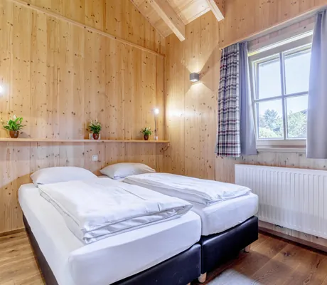 holzverkleidetes Schlafzimmer im Feriendorf Oberreit mit karierten Vorhängen