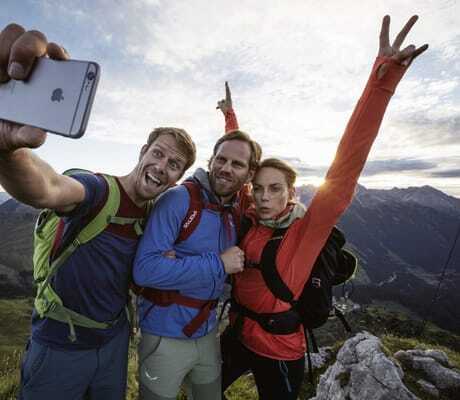 Drei Bergsteiger schießen vor Bergkulisse Selfie