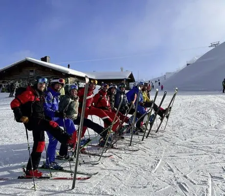 Tagende Skifahrer stehen in einer Reihe mit erhobenen Ski für Gruppenfoto Teambuilding des Berghaus Schröcken