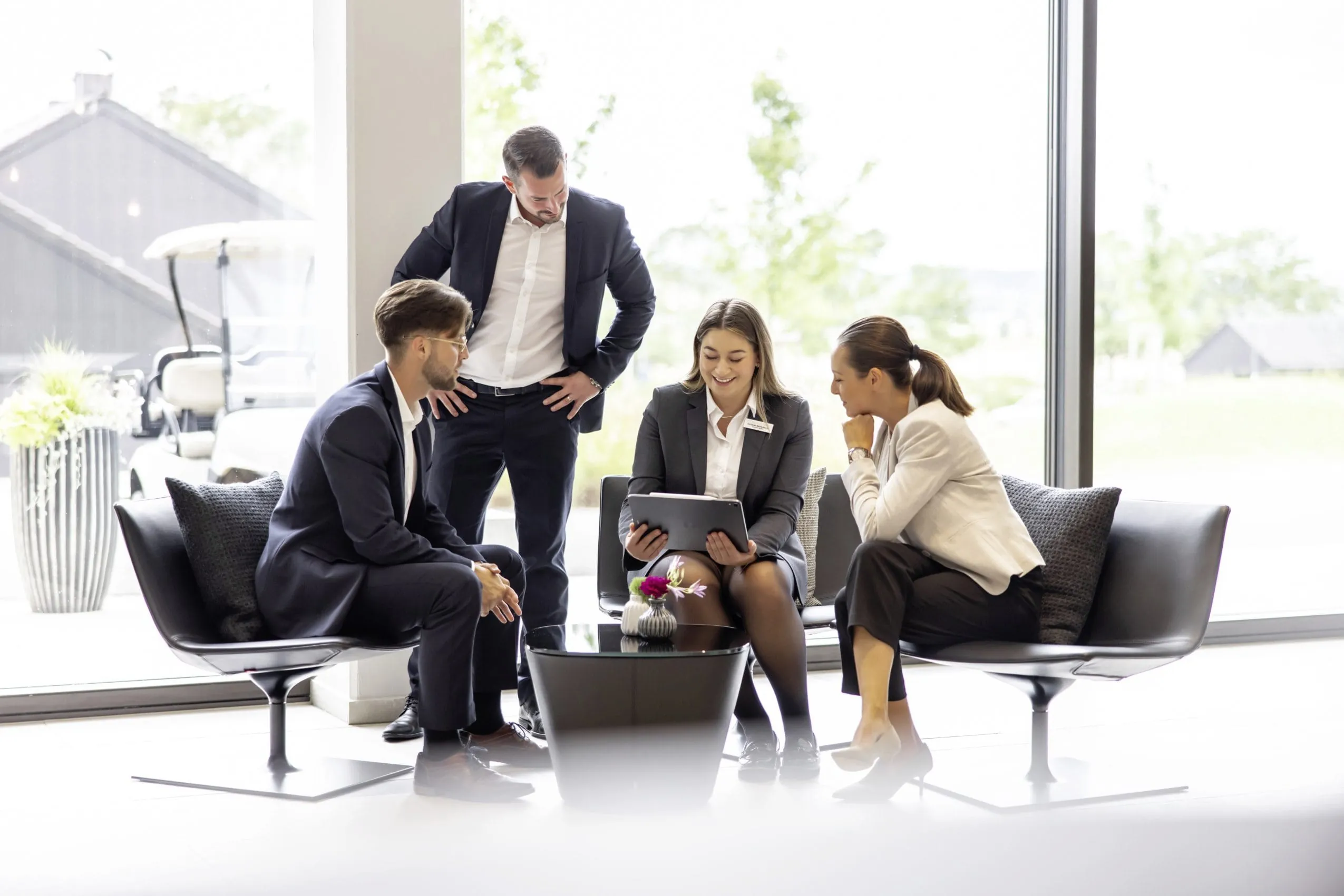 Zwei tagende M&auml;nner und Frauen versammelt um einen Laptop in einer Sitzgruppe Tagungszentrum