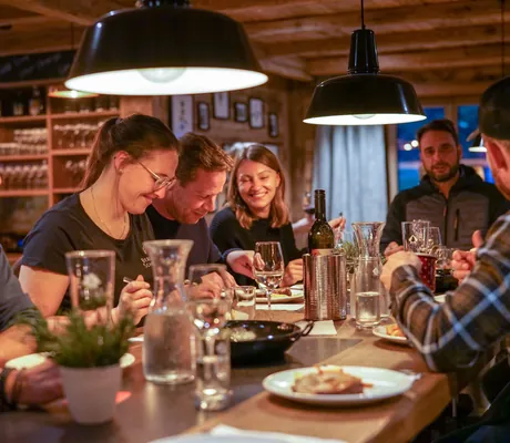 Gesellige Tischrunde beim gemeinsamen Essen in der Gaststube des Berghaus Schröcken