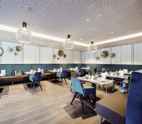 blaue Sessel im Bistro des La Maiena Meran Resort mit blauen Veloursrückwänden