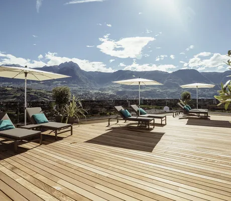 Dachterrasse mit Liegen und weißen Sonnenschirmen im La Maiena Meran Resort