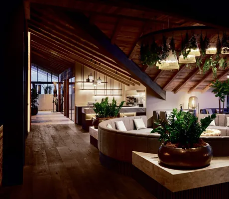 runder Couchbereich mit Hängepflanzen und großen goldenen Blumentöpfe im Hotel Quelle