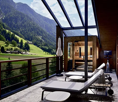 Dachterrasse mit weißen Liegen und Sauna im Hotel Quelle mit Blick ins Gsieser Tal