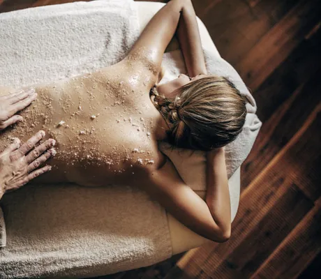 blonde Frau bekommt ein Salz-Peeling auf der Kosmetikliege des Hotel Quelle