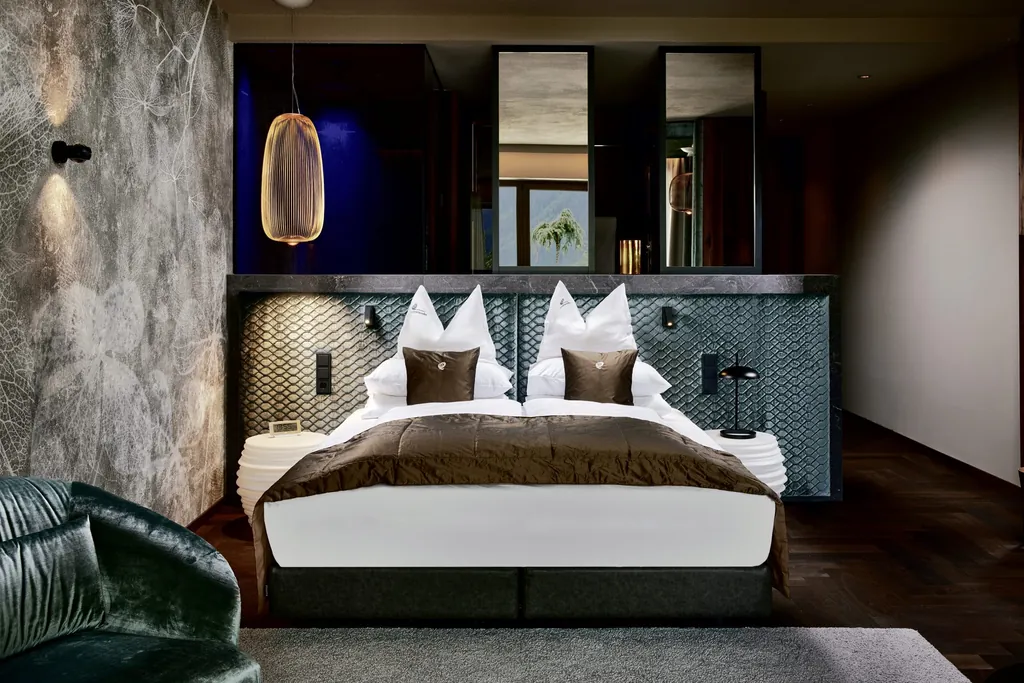 Doppelzimmer mit Blättertapete, Korb-Hängelampe und braunem Bettüberwurf im Hotel Quelle