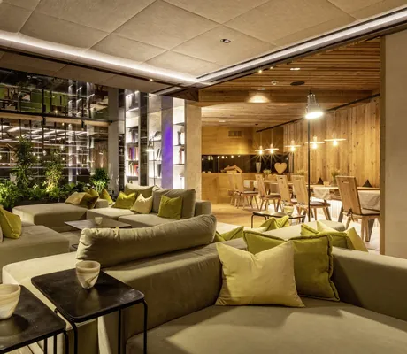 Lounge mit grünen Sitzelementen neben Restaurantbereich im Hotel Sackmann