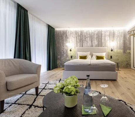 großzügiges Doppelzimmer mit Waldtapete hinter dem Bett im Hotel Sackmann