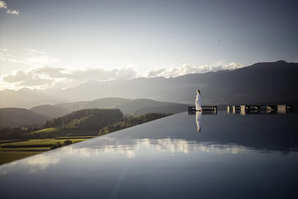 Frau in weißem Bademantel am Beckenrand des Skypool im Hotel Winkler schaut auf das Pustertal
