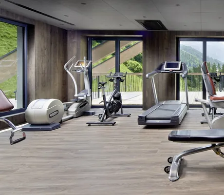 Fitnessraum im ZillergrundRock mit Technogym-Geräten und Blick aus großen Panoramafenstern