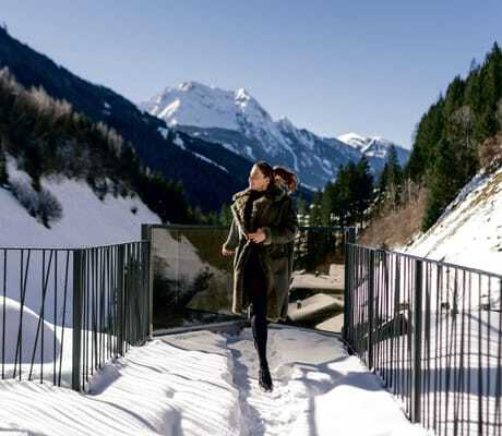 Frau mit dickem Fellmantel und Zopf läuft auf der Brücke des ZillergrundRock