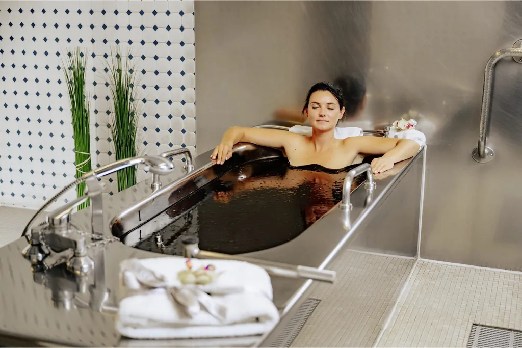 Junge Frau sitzt in Badewanne und genießt ein Moorbad