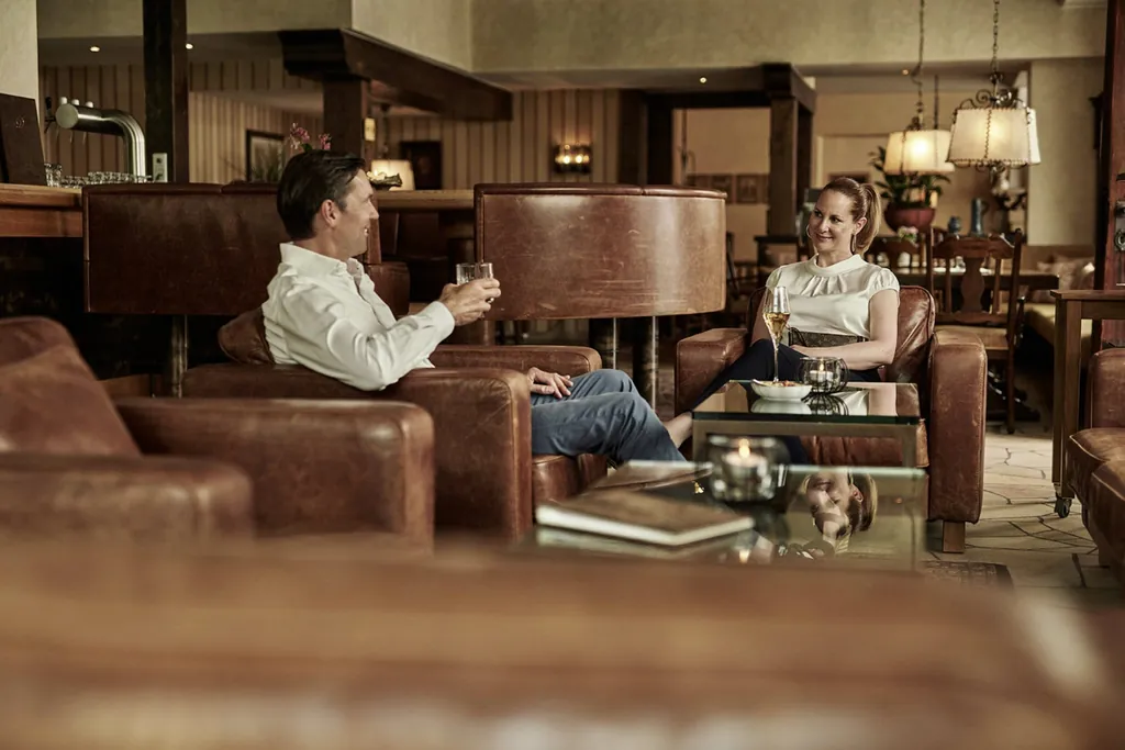 Ehepaar sitzt mit Getränken in Ledersesseln in der Lounge des Hotel Deimann
