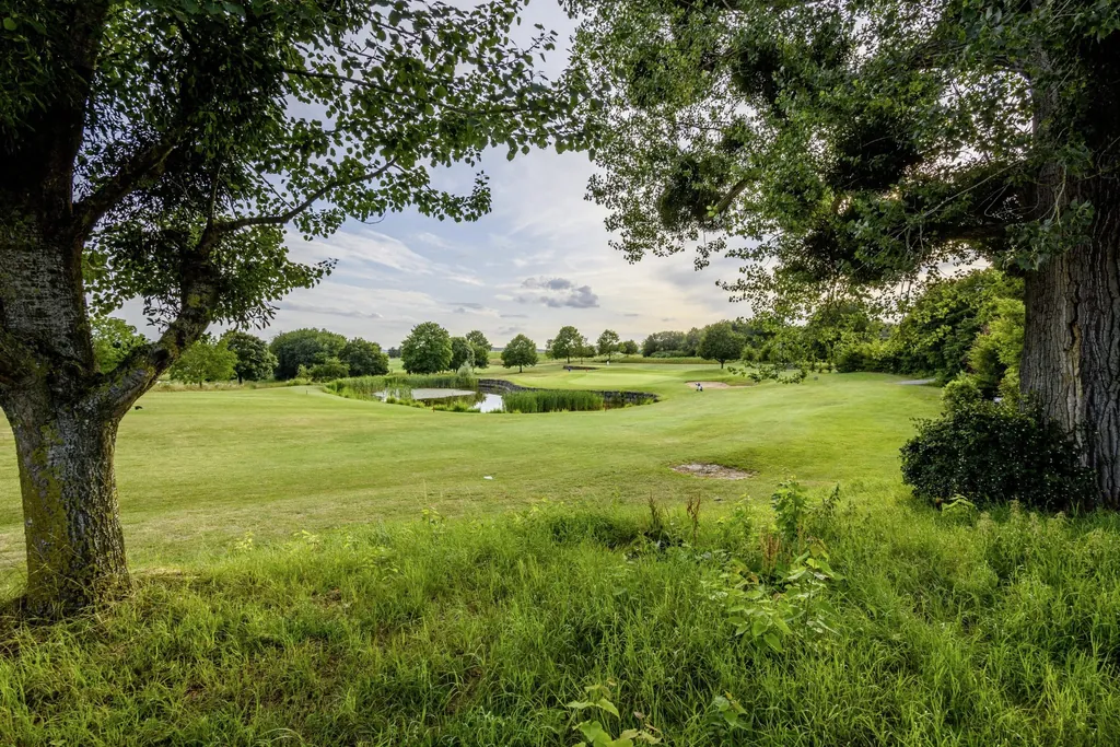 Blick durch zwei Bäume auf den Golfplatz in Zweiflingen mit einem kleinen See