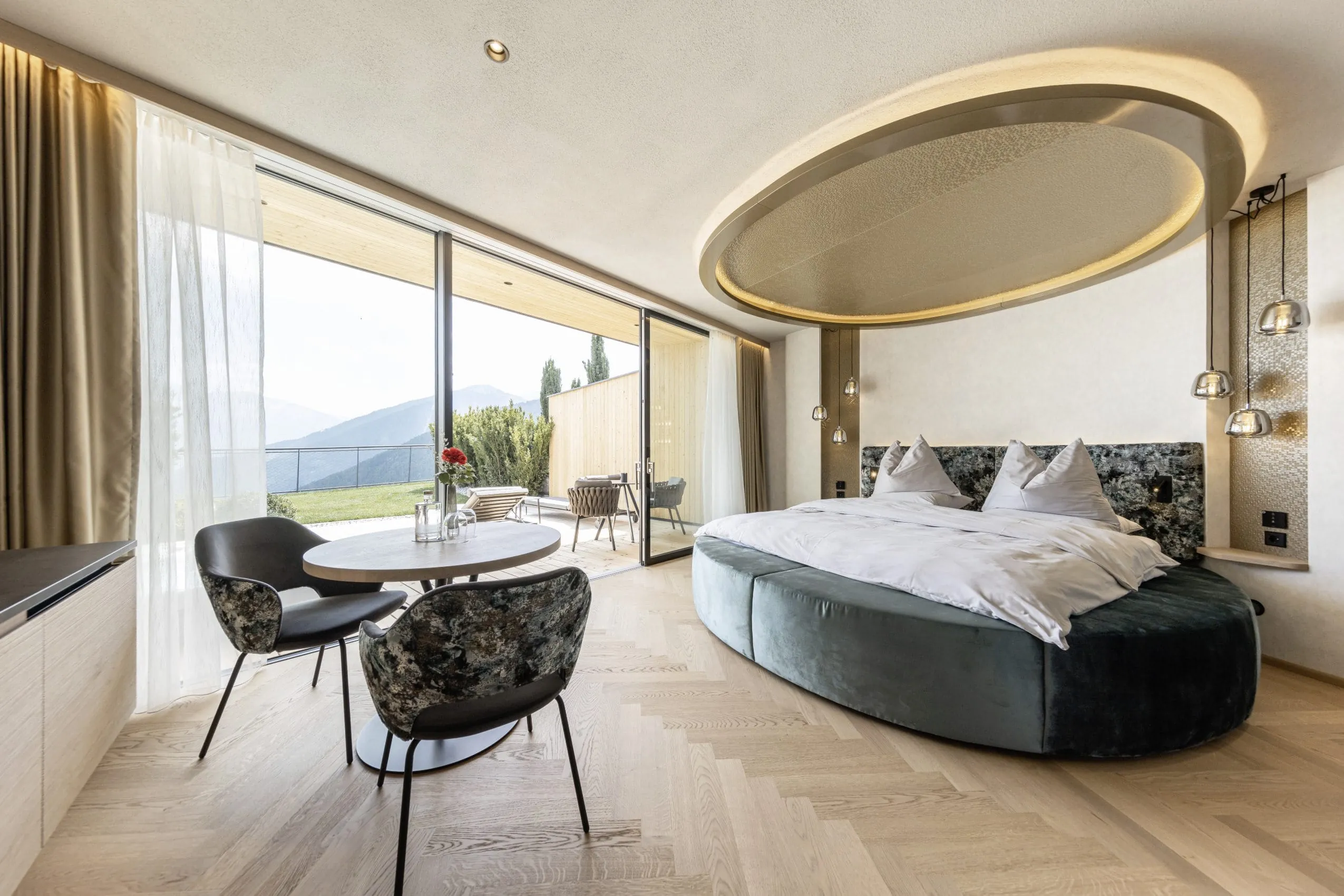 Suite mit rundem Bett und großer runder Deckenleuchte im Wellnesshotel Das Gerstl in Südtirol