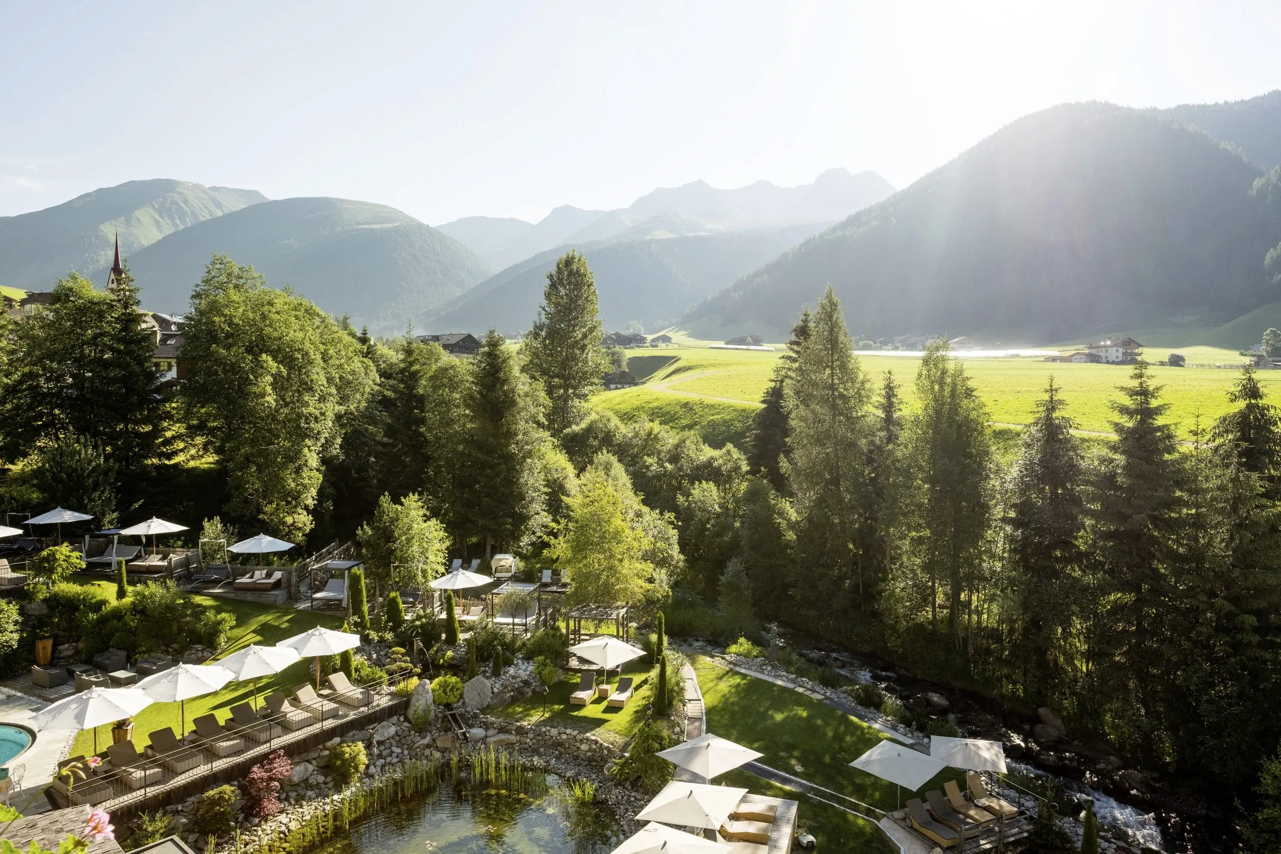 Wellnesspark im Hotel Quelle mit Naturbadeteich und Liegebereich mit Schirmen