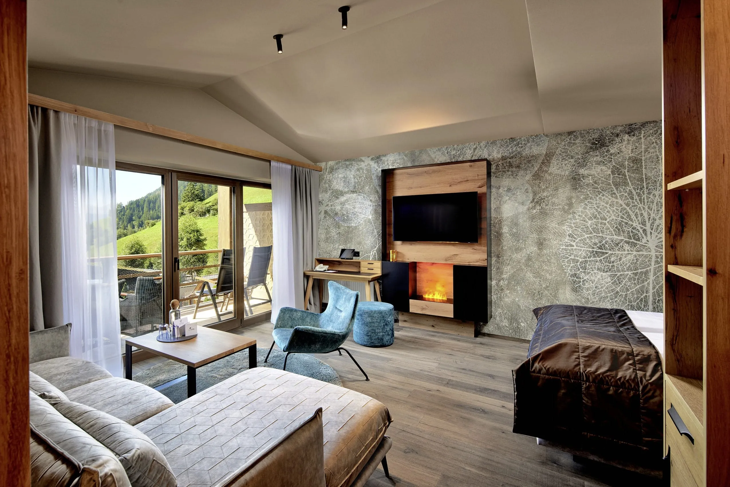 Zimmer mit türkisen Sitzmöbeln und Kamin im Wellnesshotel Quelle in Südtirol