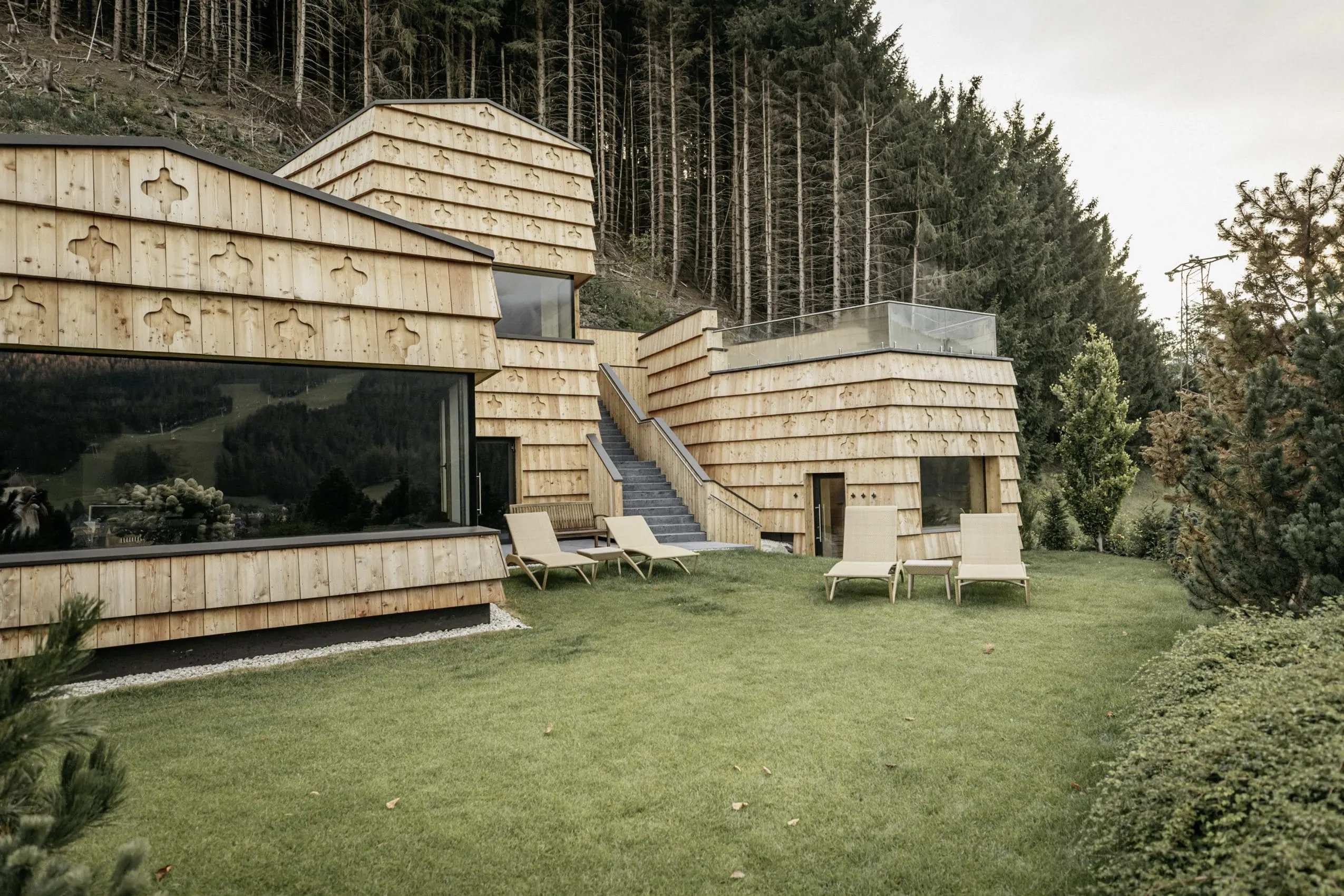 Schindelfassade des Naturhotel Leitlhof mit Liegen im Garten