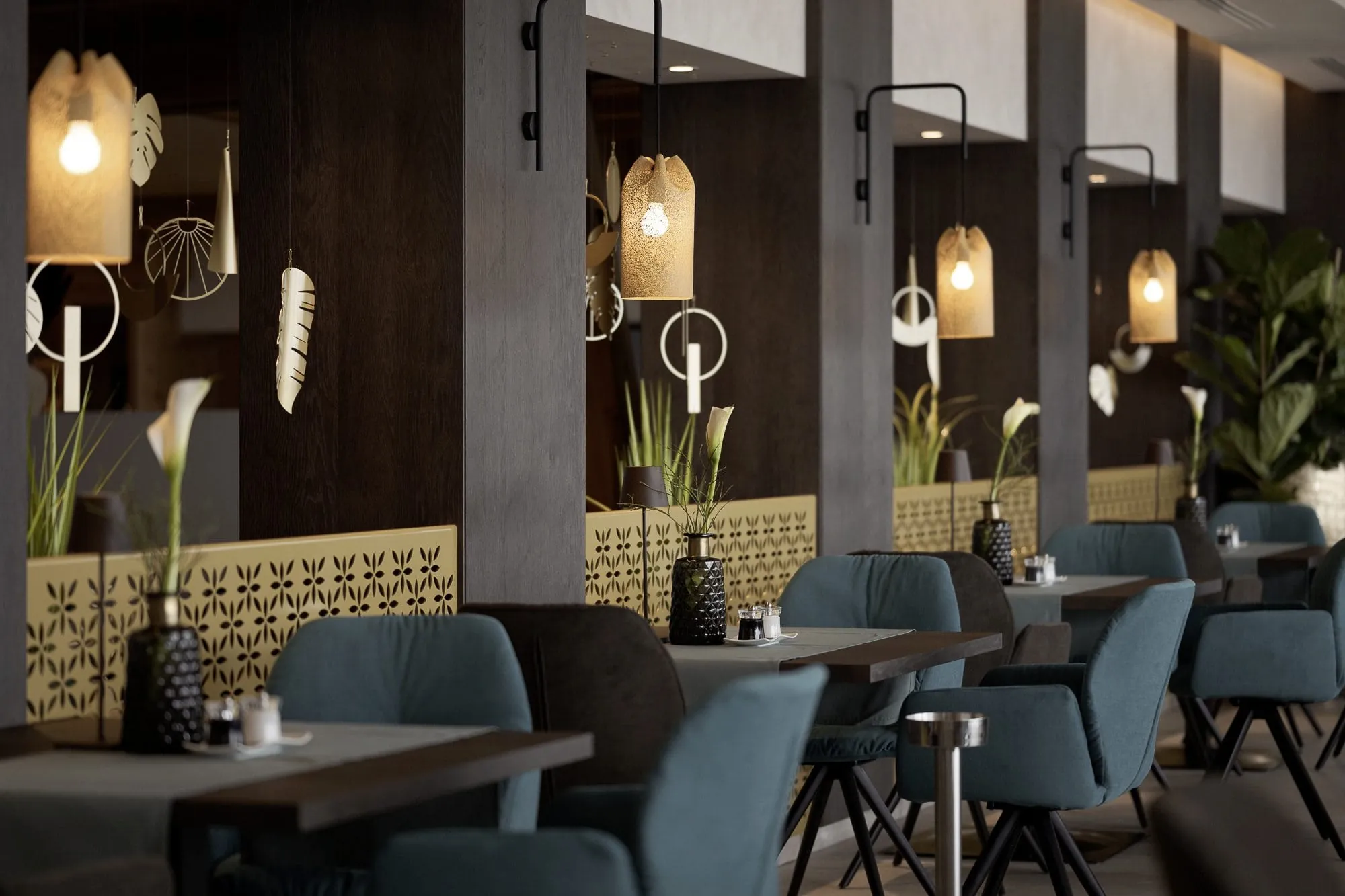 Restaurant mit blauen Sesseln und Hängeleuchten über jedem Tisch im La Maiena Meran Resort