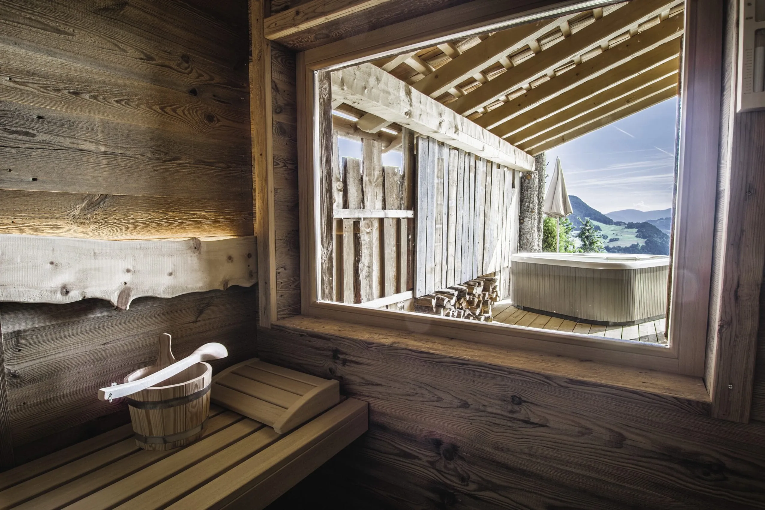 Blick von der Sauna auf den Whirlpool auf der Terrasse im Chalet Zu Kirchwies