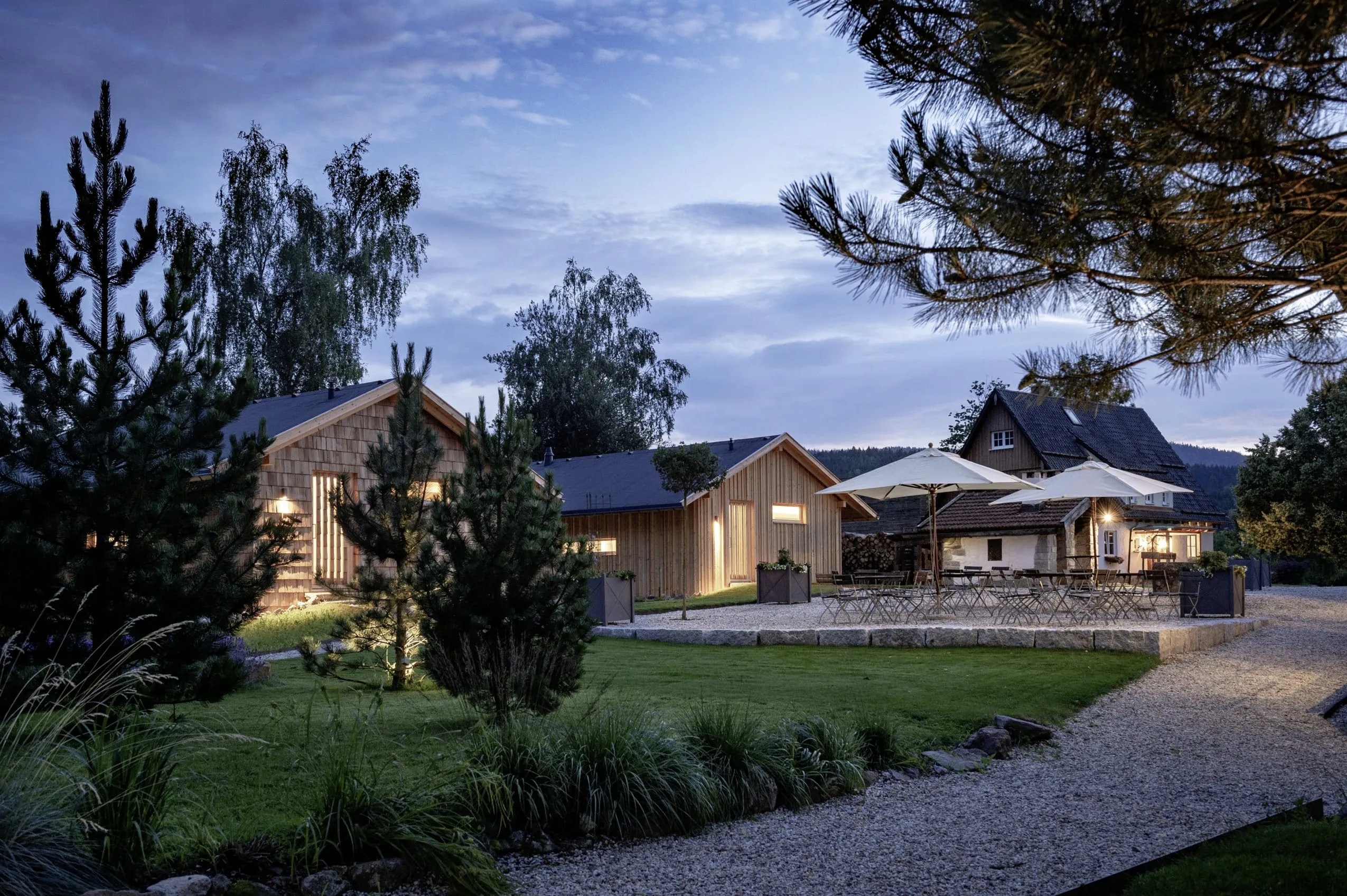 Au&szlig;enansicht des Chaletdorfs Forstgut mit Biergarten-Terrasse in der D&auml;mmerung