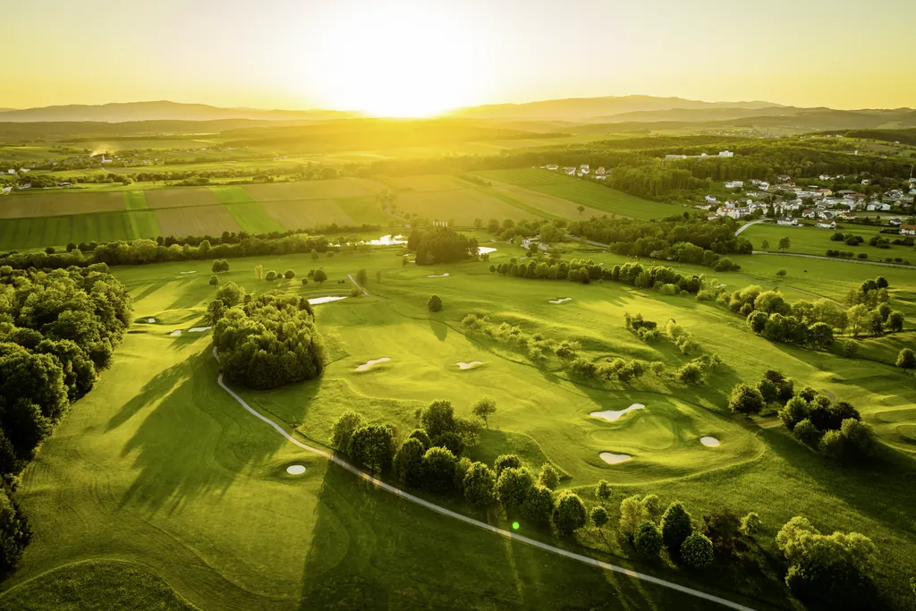 Blick auf den sanft-hügeligen Golfplatz des Reiters Supreme im Burgenland mit untergehender Sonne im Hintergrund
