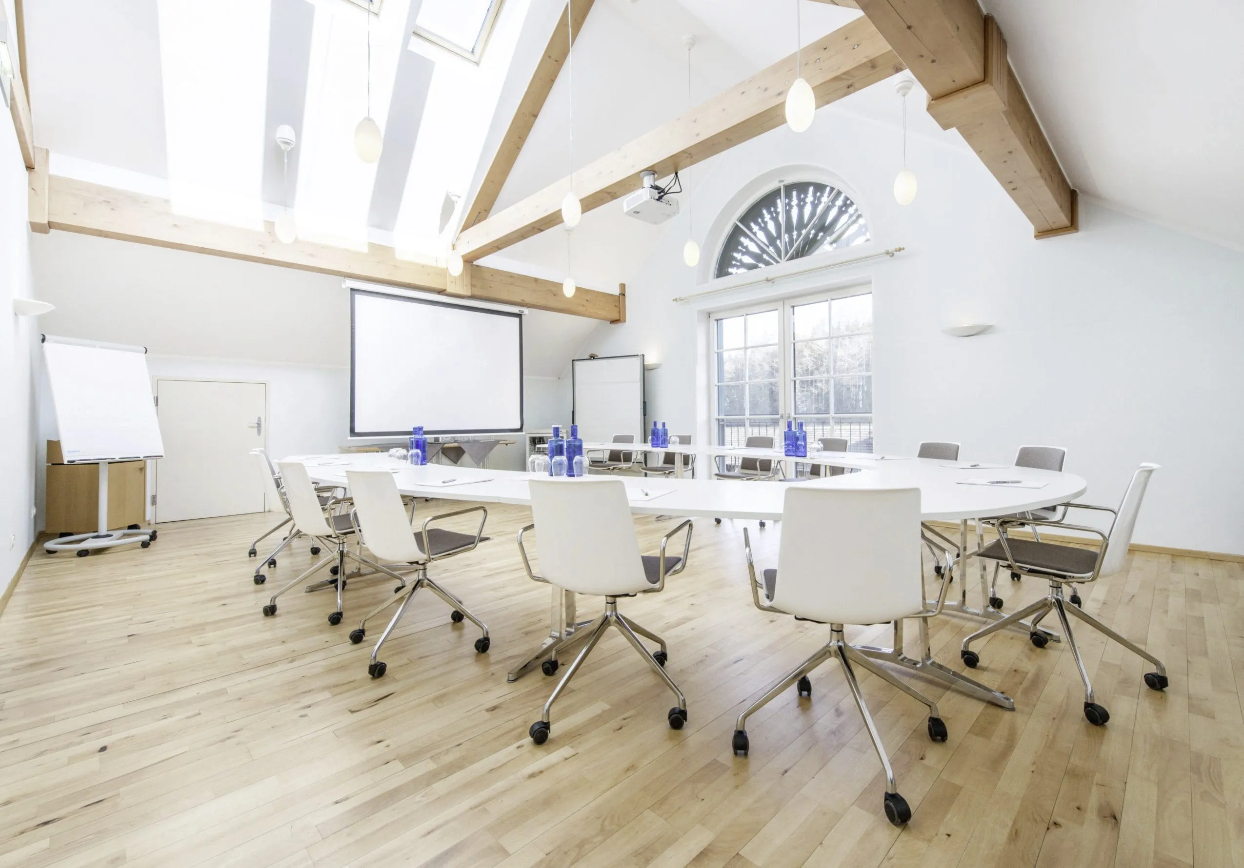 Heller Tagungsraum mit Parkettboden, Thermenfenstern und Leinwand im Schlossgut Oberambach
