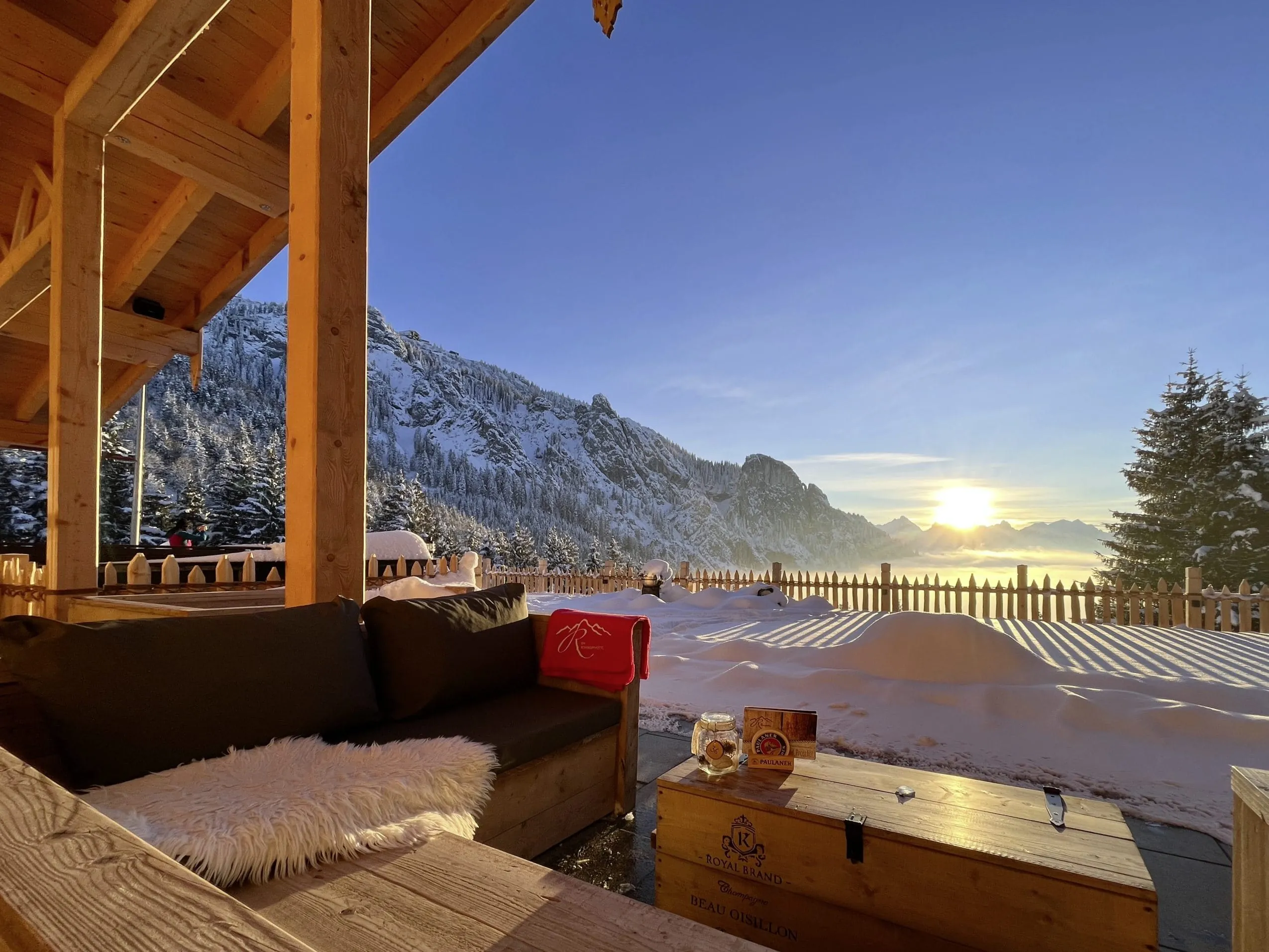 Terrasse der Rohrkopfh&uuml;tte des Das R&uuml;bezahl mit Sitzecke unter dem Dach und Blick auf den Tegelberg