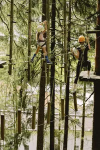 Kletternde Frau und Mädchen im Hochseilgarten des Familienresort Buchau