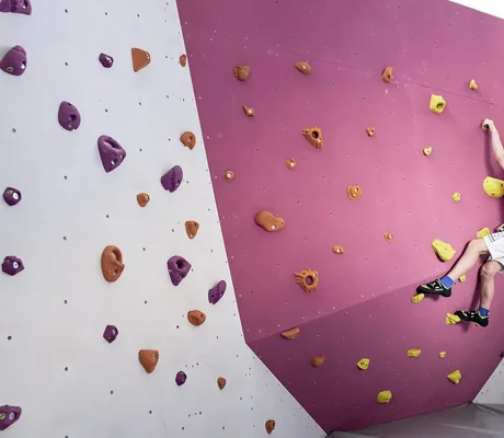 Junge klettert an der Boulder-Kletterwand im