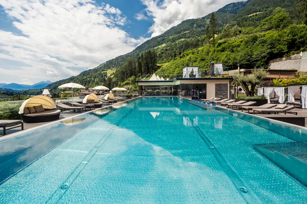 Outdoorpool des Quellenhof Luxury Resort Passeier mit Blick auf die umgebende Südtiroler Bergwelt