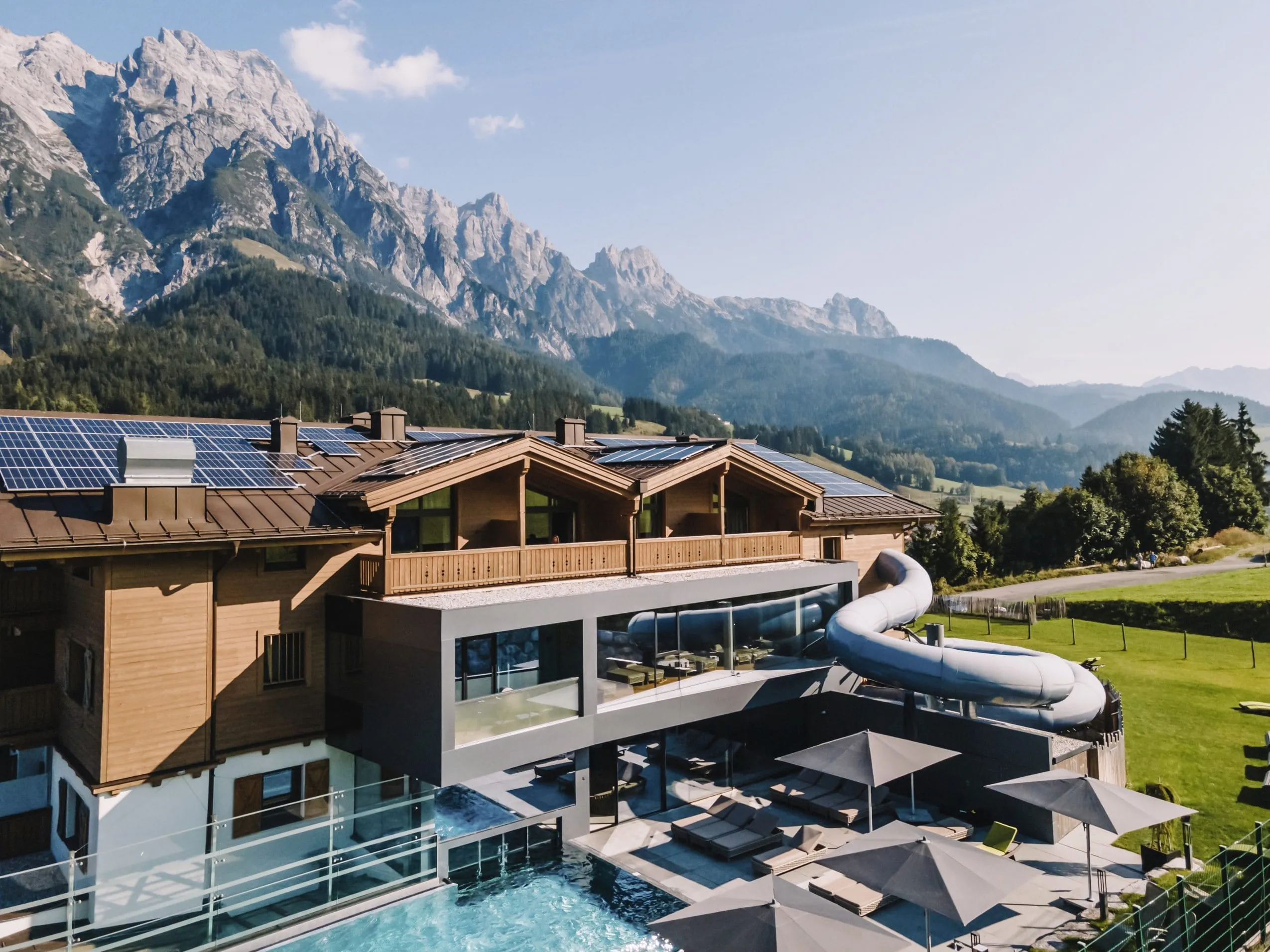 Aussenaufnahme des Good Life Resort Riederalm mit Outdoorpool und Bergblick in Leogang