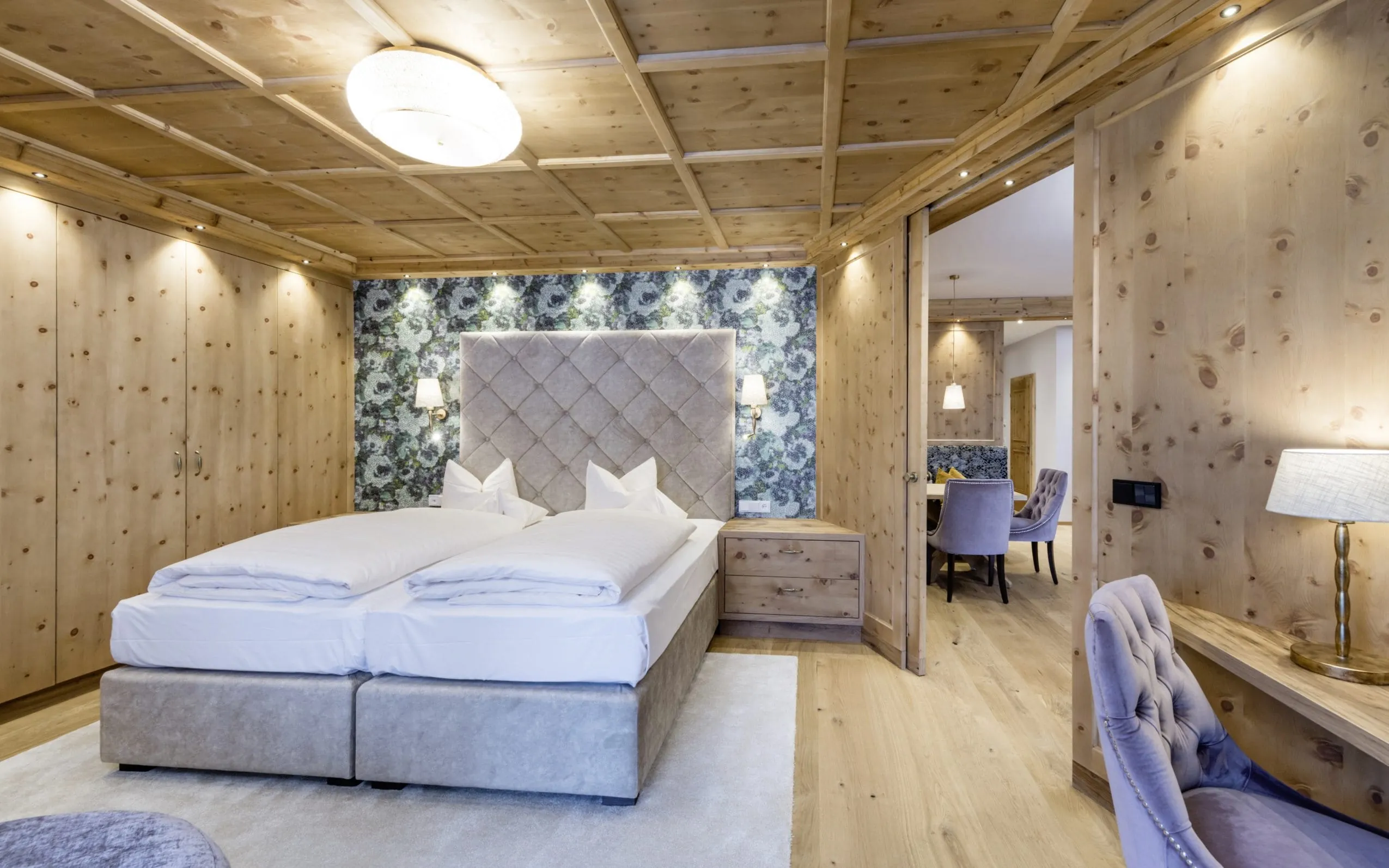 Elegantes holzverkleidetes Doppelzimmer mit grauem Boxspringbett im Peternhof Wohlfuehlresort