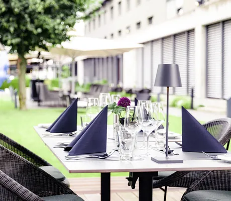 Eingedeckter Tisch vor großem Glasfenster mit Blick Richtung Hotelgarten