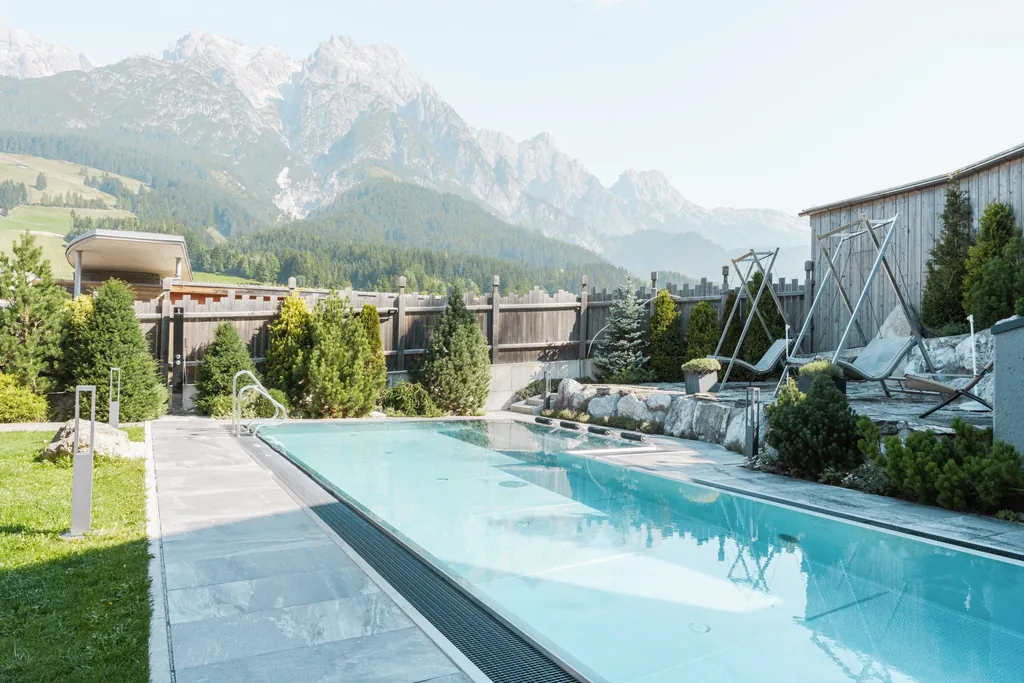 Thermalwasser-Außenpool mit Schauekelliegen und Bergblick im Good Life Resort Riederalm