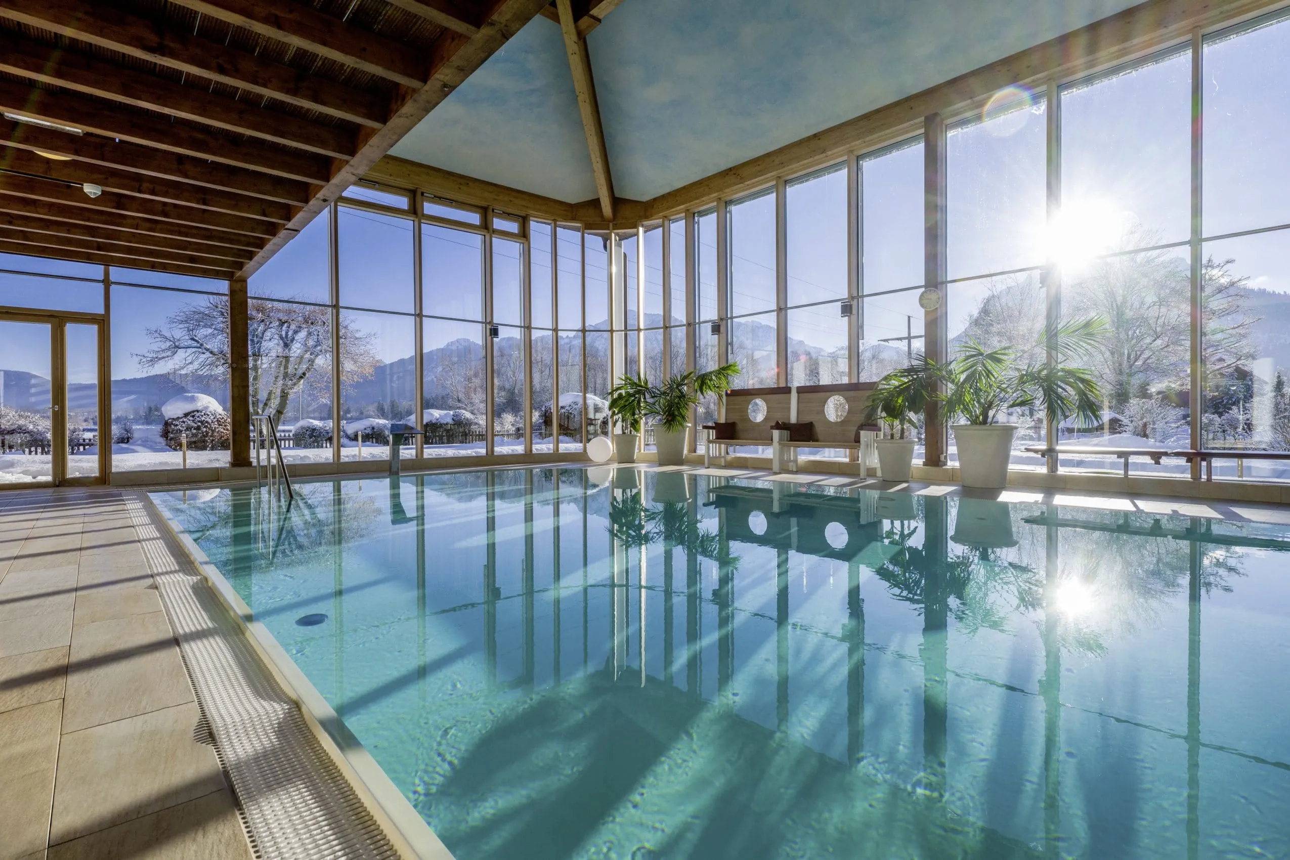 Indoorpool in verglastem Geb&auml;ude mit einfallender Wintersonne im Wellnesshotel Sommer