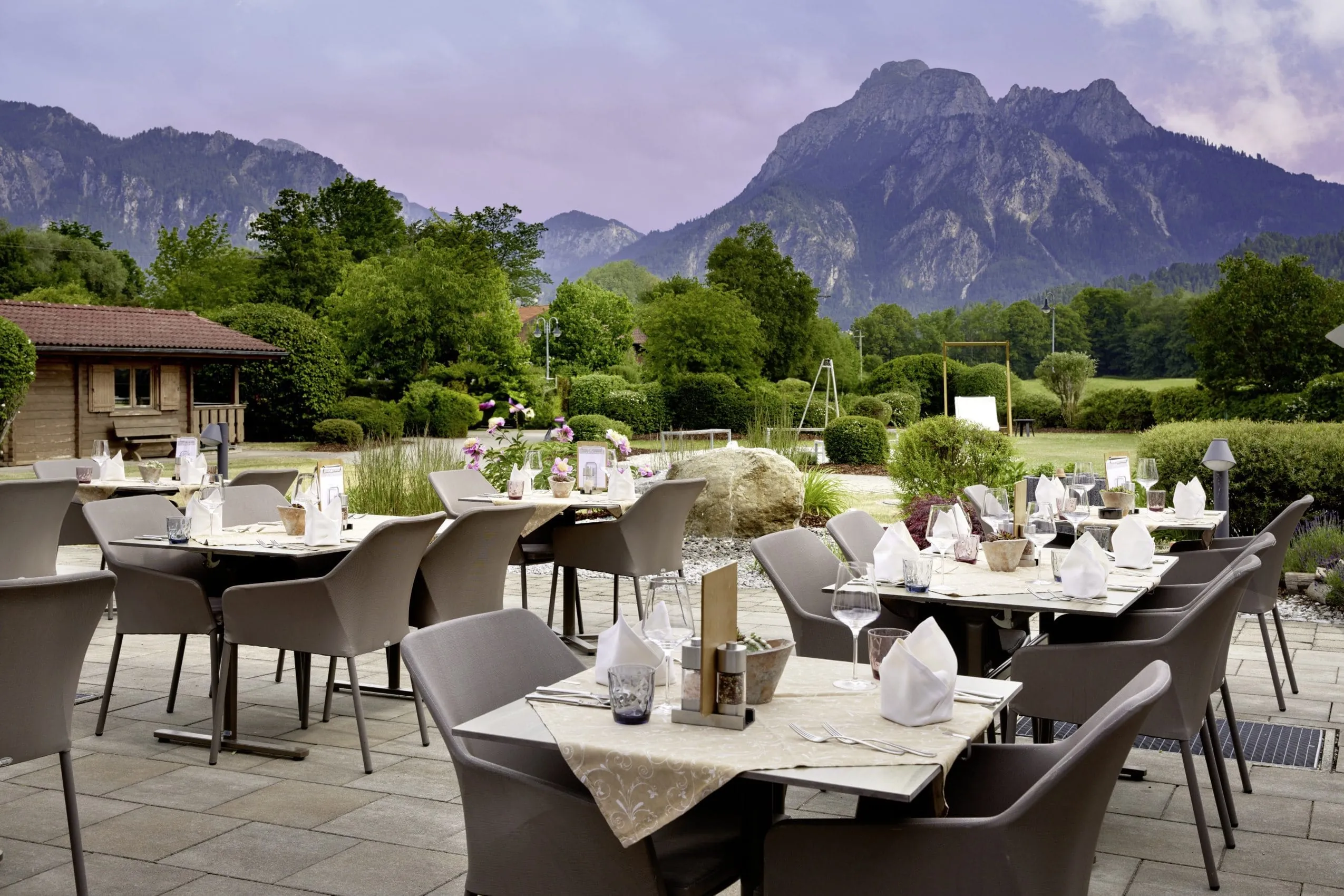 Eingedeckte Tische am Abend auf der Restaurantterrasse im Wellnesshotel Sommer und Blick auf die Allgäuer Alpen
