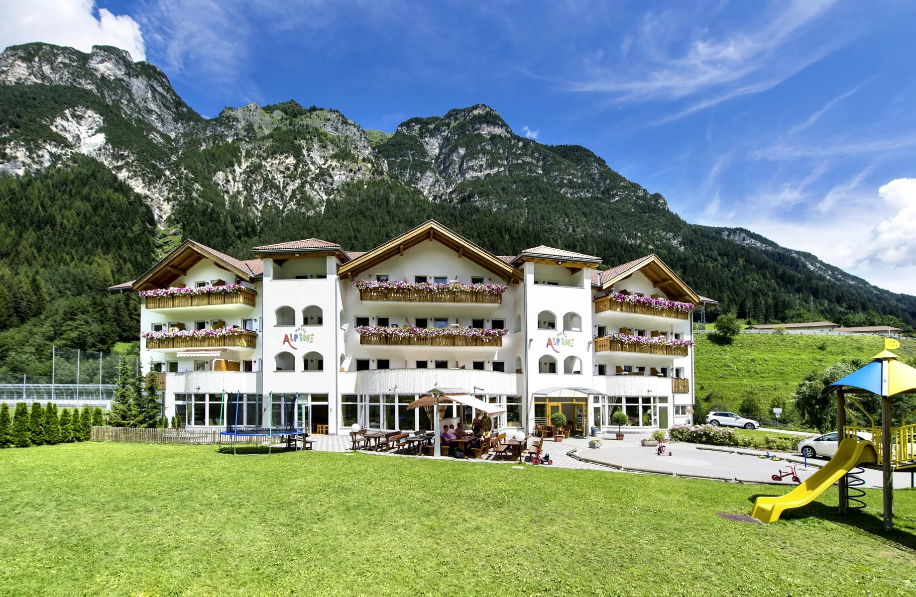 Aussenaufnahme Hotel Alpin mit Outdoorspielplatz und Wiese vor Alpenhauptkamm mit Weißwandspitze im Pflerschtal