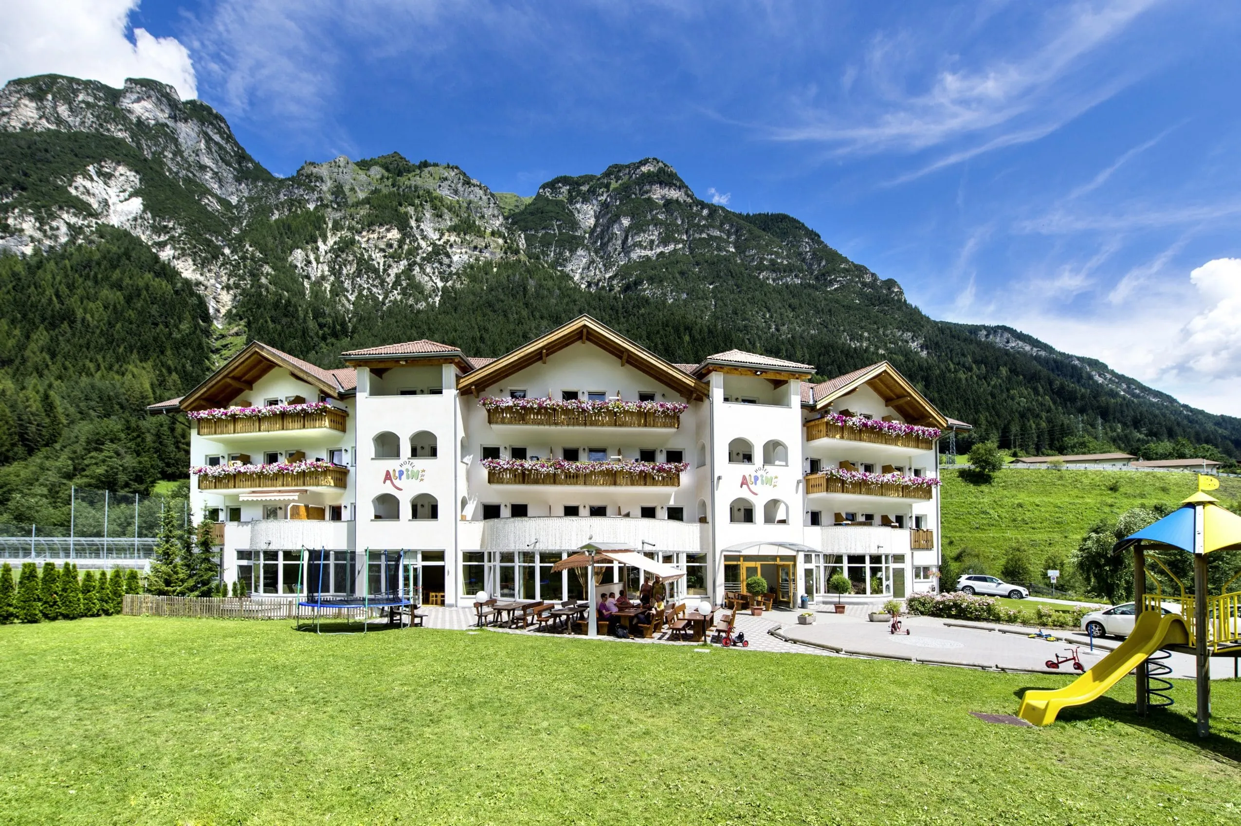 Aussenaufnahme Hotel Alpin mit Outdoorspielplatz und Wiese vor Alpenhauptkamm mit Weißwandspitze im Pflerschtal