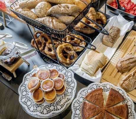 Frühstücksbuffet mit bayerischen Brezen, selbstgebackenen Muffins und veganen Brotaufstrichen im Restaurant „KOOS Bowls & Bar“